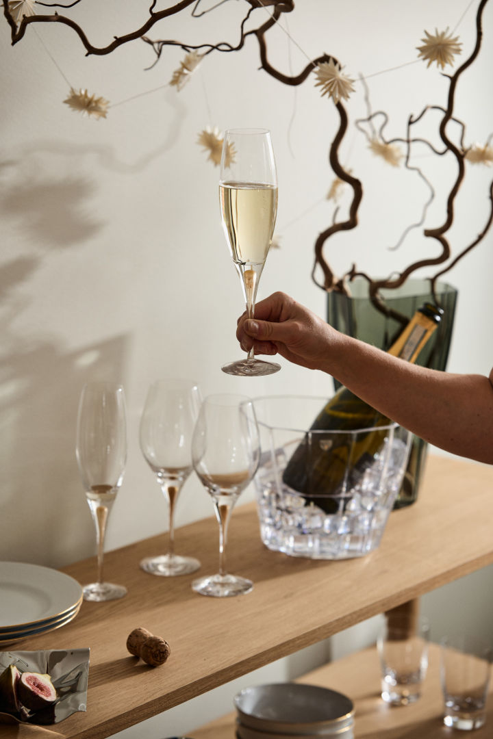 En hånd holder opp Intermezzo champagneglass fra Orrefors.