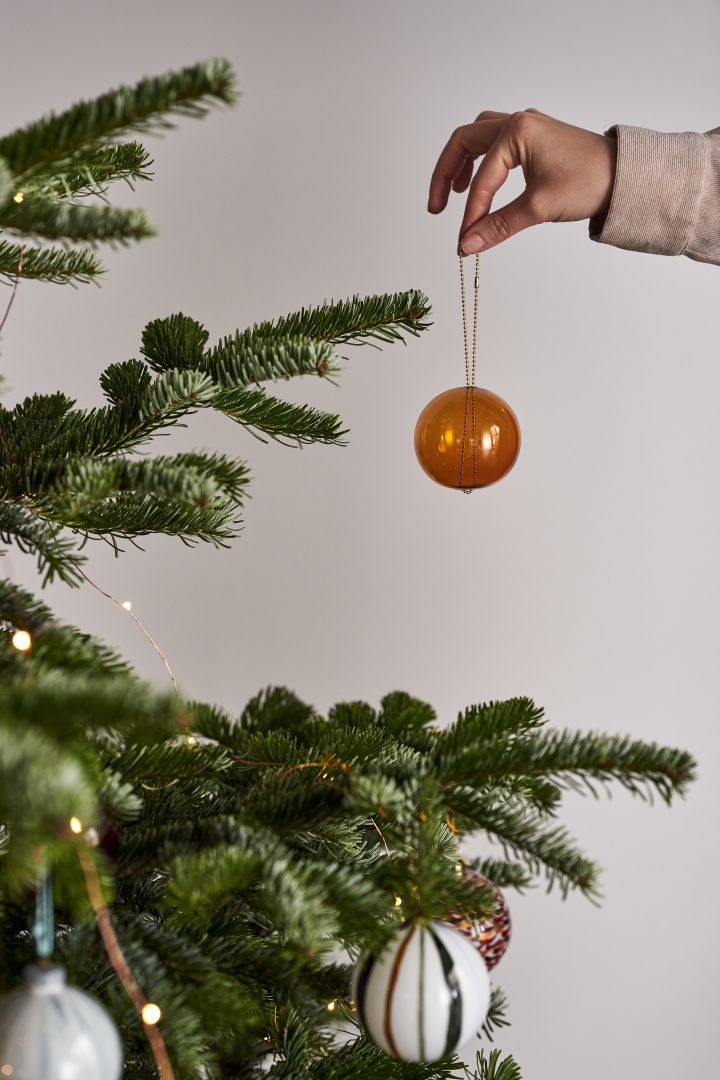 Pynt juletreet med juletrepynt i 4 stiler i henhold til Nest Trends - Nurture, Share, Boost and Cultivate. Her ser du Monili julekule fra AYTM en vakker ravfarge.