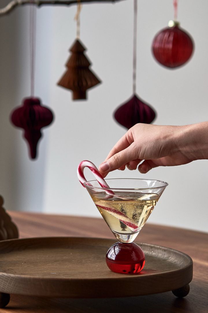 Server en enkel juledrink med gløgg og bobler i et Spice drinkglass fra Byon med en polkagris som garnityr. 