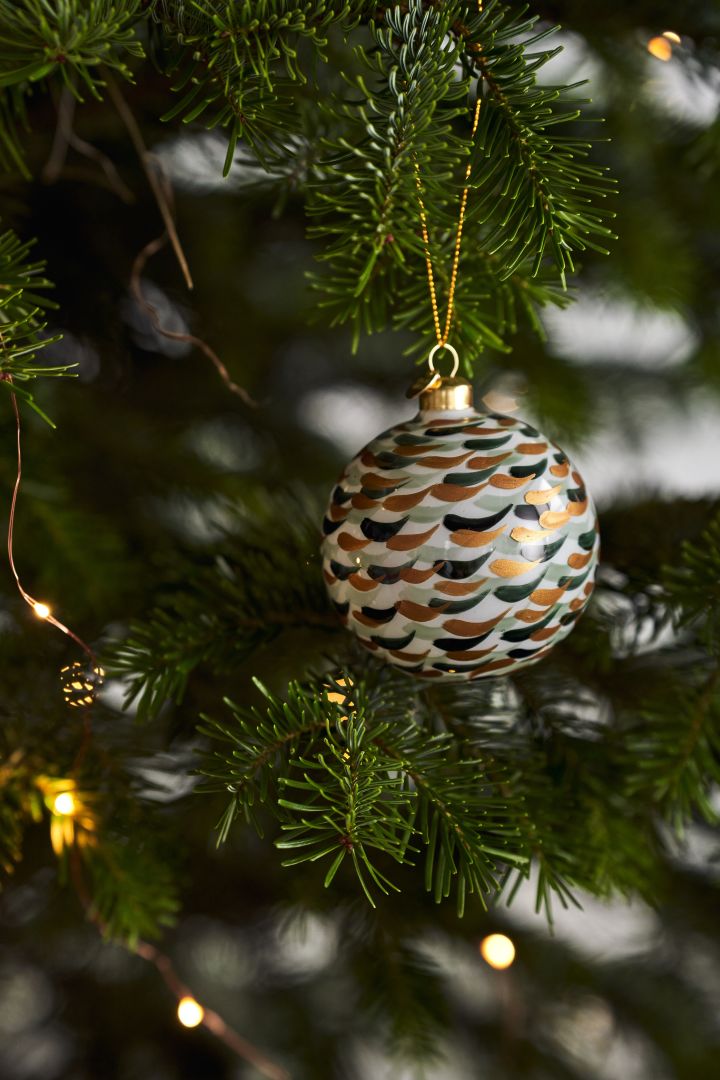 Pynt juletreet med årets juletrepynt i 4 forskjellige stiler i henhold til Nest Trends - Nurture, Share, Boost og Cultivate. Her ser du Souvenir julekule med penselstrøk fra Holmegaard.