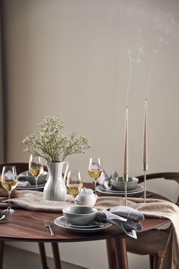 Et festlig bord med stearinlys, engblomster i en karaffel av Pli Blanc og Swedish Grace porselen i hvitt og grått.