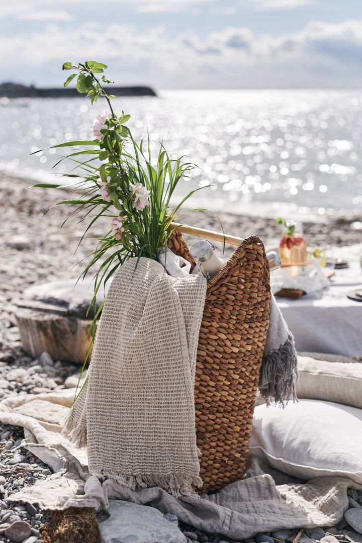 Piknikkurv fullpakket med tepper og termos for en piknik på stranden.
 
