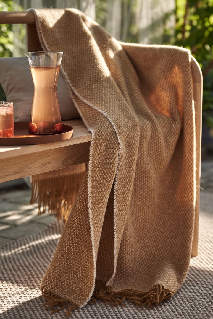 Tips til koselig uteplass - innred uteplassen din med koselige og myke tekstiler som Scandi Livings ullpledd i en nydelig oransje farge.