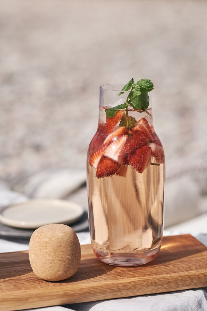 Gode sommerdrinker - sangria med jordbær toppet med mynte servert i en glasskaraffel.